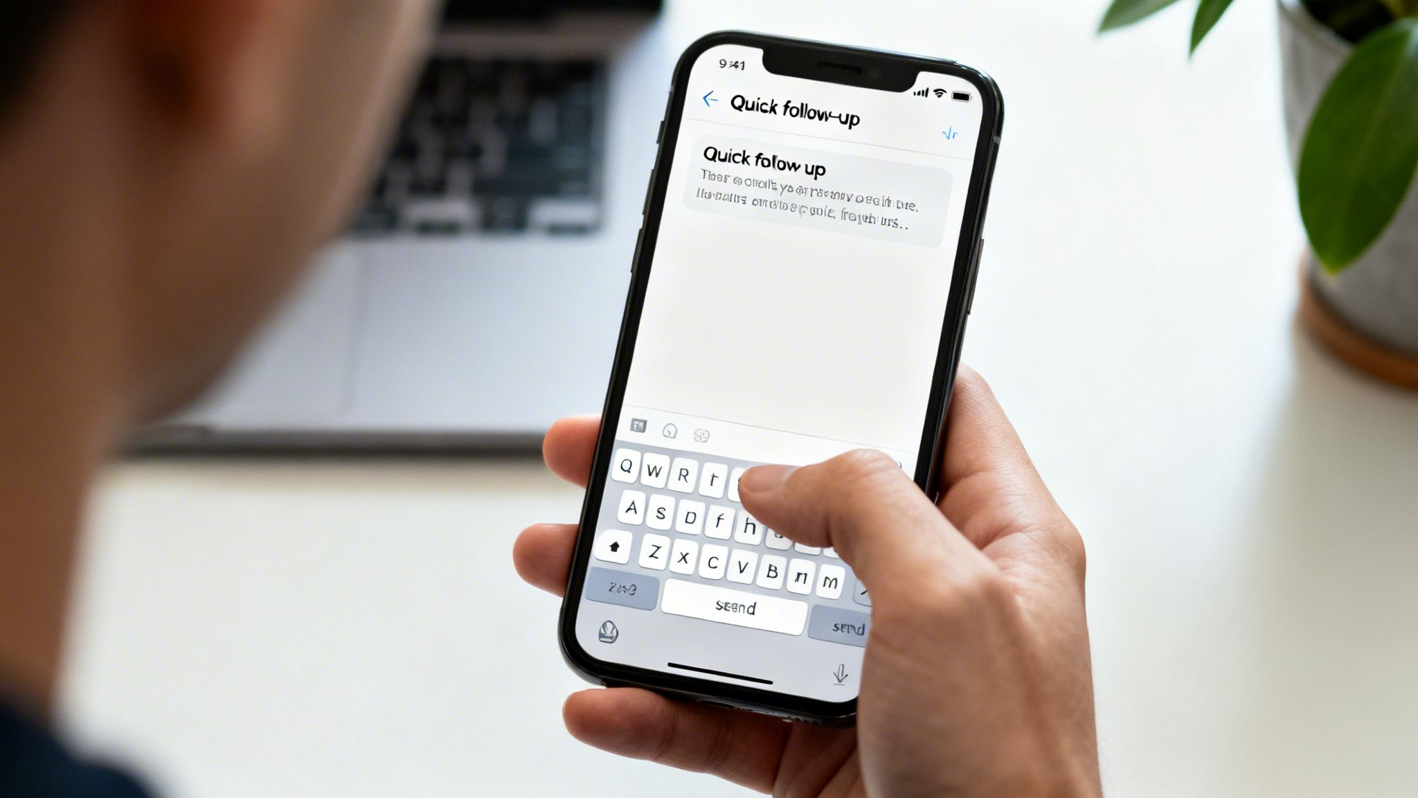 A person types a 'Quick follow-up' message on an iPhone, with a laptop in the background.