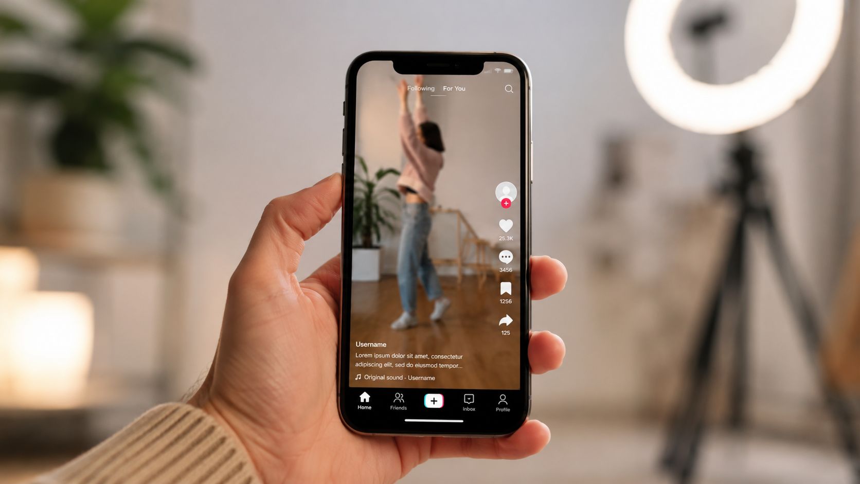 A hand holding a smartphone displaying a social media video feed of a person dancing.